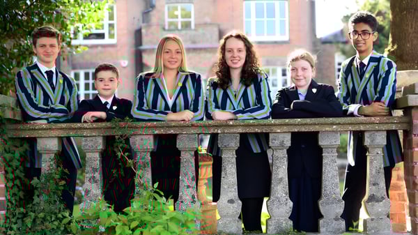 Estudiantes de la Wisbech Grammar School están en un puente de madera rodeados de vegetación verde.
