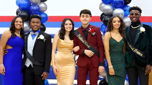 Un grupo de personas en ropa formal posan frente a globos azules y plateados en el terreno de la Wisconsin Lutheran High School.