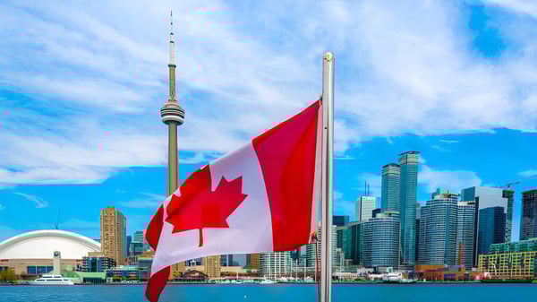 Una gran bandera canadiense ondea frente al horizonte de Toronto con la Torre CN en el campus del Woburn Collegiate Institute.