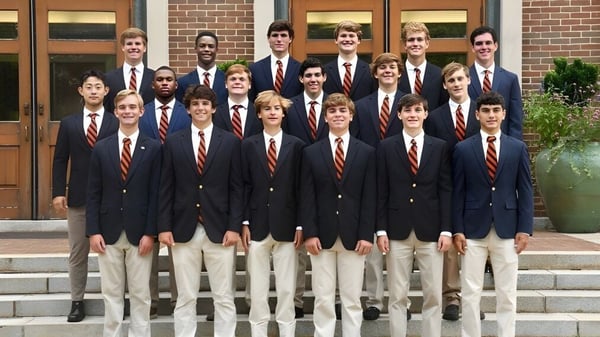 Estudiantes de la Woodberry Forest School están en la escalera frente a un edificio de ladrillo con una puerta de madera.