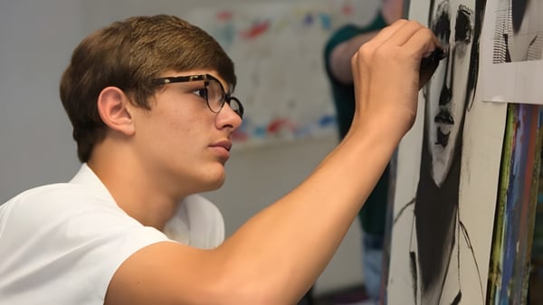 Un niño con gafas está frente a una pared con coloridas obras de arte en el campus de la Woodberry Forest School.