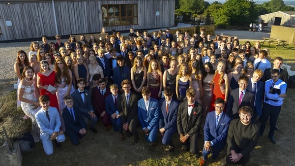 Un grupo de estudiantes está de pie frente a un edificio de madera en el área exterior de la Woodroffe High School.