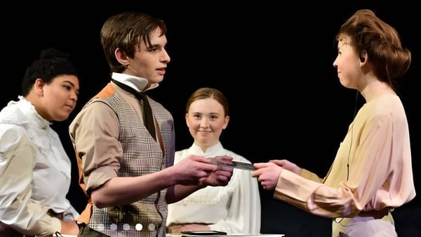 Estudiantes de la Worcester Academy en trajes históricos representan una escena con una entrega durante una actuación en el campus.