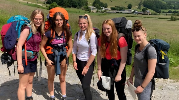 Un grupo de estudiantes del Wrekin College está junto en ropa de senderismo frente a un paisaje montañoso.