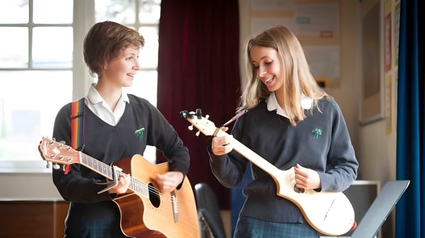 Dos alumnas de la Wychwood School tocan juntas guitarras acústicas en un aula.