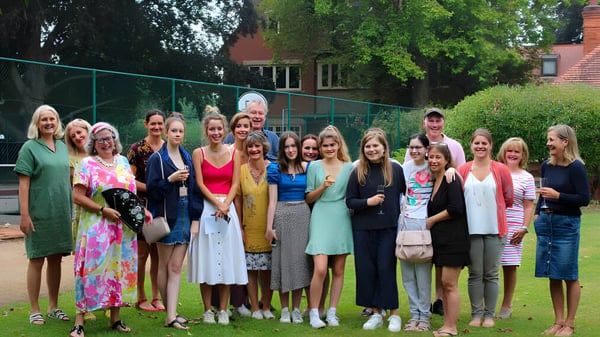 Un grupo de alumnas de la Wychwood School está en un campo con árboles y edificios al fondo.