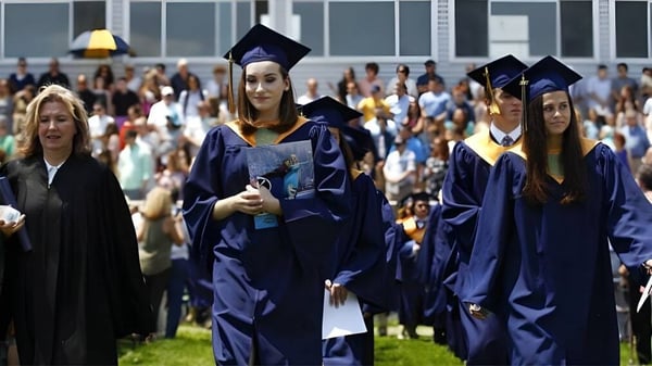 Un grupo de graduados en togas azules está frente a un edificio en el campus de Wyoming Seminary College Preparatory.