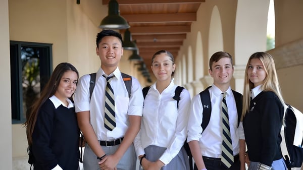 Un grupo de estudiantes está de pie en un pasillo con techos de madera en el campus de la Xavier College Preparatory High School.