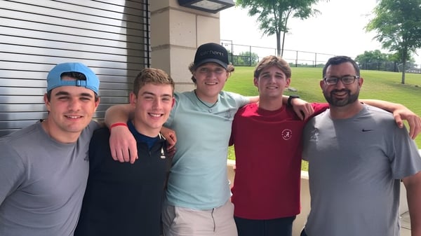 Cinco estudiantes están de pie en el área exterior frente a un edificio en el campus de la Xavier High School.