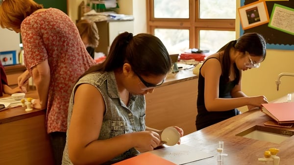 Tres estudiantes de la Yehudi Menuhin School están sentadas en una mesa y están ocupadas leyendo y escribiendo.