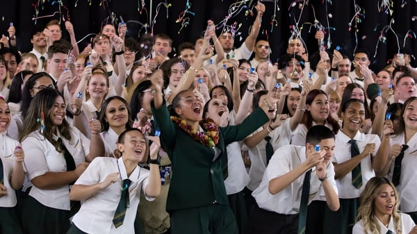 Estudiantes de la Yeronga State High School celebran juntos con los brazos en alto en un evento.